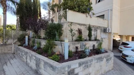 ערוגות מטופחות וגינון מעוצב בכניסה לבניין