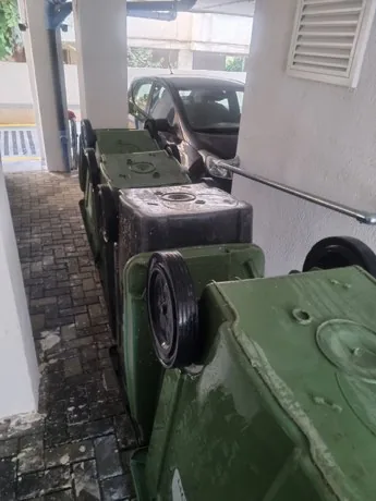 פחי אשפה ירוקים מסודרים במעבר לחדר האשפה של הבניין