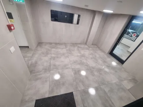 לובי כניסה נקי עם ריצוף אריחים אפורים ושטיחון כניסה