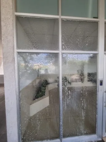 דלת כניסה מזכוכית לפני ניקוי — לכלוך מצטבר על השמשות