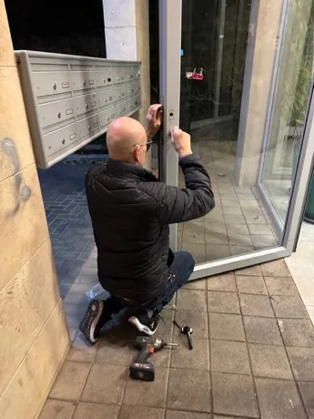 עובד מתקן את מנעול דלת הכניסה, ליד תיבות הדואר של הבניין